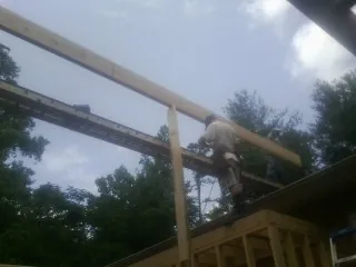 Carpenter setting a ridge beam over a new addition frame in Kathryn