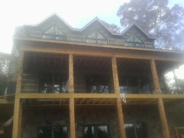 Dormers and porch framing on a large log home under construction — Roof Coating work by our crew in Kathryn