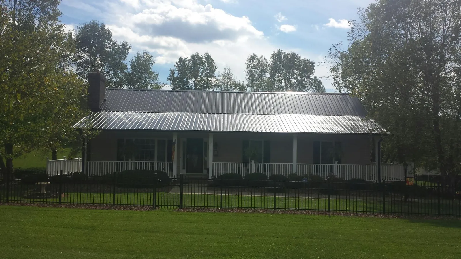 Gray metal roof on a brick ranch with a full width front porch — Gutter Guard Installation work by our crew in Kathryn