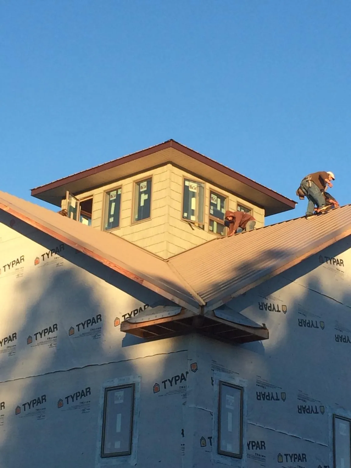 Roofers working around a rooftop cupola on a new metal roof at sunset — Roof Waterproofing in Kathryn by Roofing Brothers